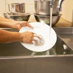 hand washing dishes in a commercial kitchen